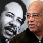 Former-Chapel-Hill-NC-Mayor-Howard-Lee-stands-next-to-a-1970s-photo-of-himself-at-the-Chapel-Hill-Library